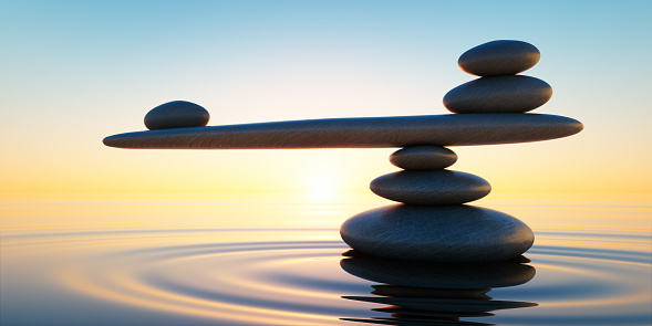 Stack of stones in calm water with seesaw in the evening sun